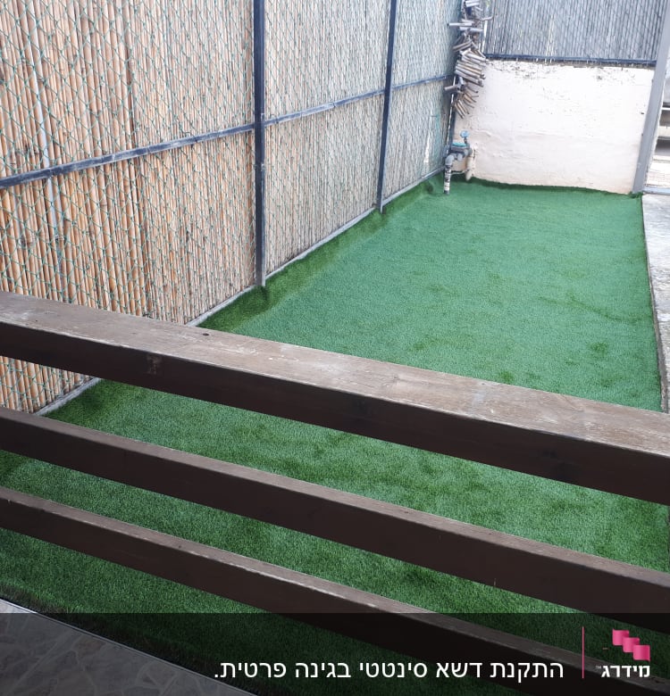 דשא סינתטי על הקרקע ליד גדר מתכת